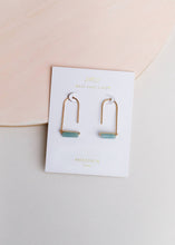 Load image into Gallery viewer, Pair of gold and turquoise earrings on a branded card against a light pink background

