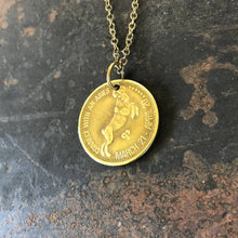 Load image into Gallery viewer, Gold zodiac pendant necklace on a textured dark surface
