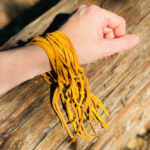 Load image into Gallery viewer, Hand wearing a yellow bracelet on a wooden surface
