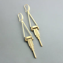 Load image into Gallery viewer, Gold earrings with geometric design on a gray background
