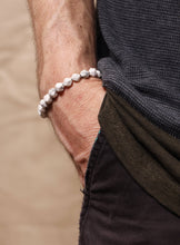 Load image into Gallery viewer, Close-up of a wrist wearing a white beaded bracelet on a blurred background
