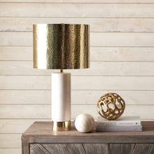 Load image into Gallery viewer, Decorative table lamp with gold and white base on a wooden surface against a wooden wall.
