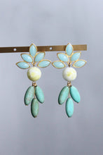 Load image into Gallery viewer, Pair of earrings with light blue floral tops and green leaves on a grey background 
