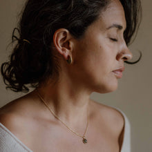 Load image into Gallery viewer, Close-up of a woman wearing a gold necklace with a pendant against a neutral background
