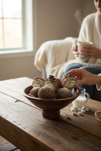 Load image into Gallery viewer, Person touching a wooden bowl of chocolate donuts on a wood table
