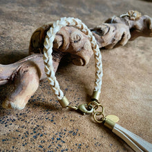 Load image into Gallery viewer, Bracelet with braided design and gold accents on a textured surface
