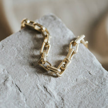Load image into Gallery viewer, Gold chain necklace on a textured stone surface
