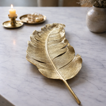Load image into Gallery viewer, Gold leaf-shaped decorative item on a marble surface with a candle and vase in the background.
