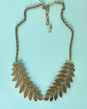 Load image into Gallery viewer, Gold leaf necklace on a light blue background
