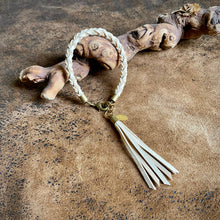 Load image into Gallery viewer, Bracelet with tassel on a textured surface

