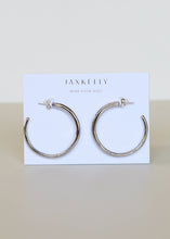 Load image into Gallery viewer, silver hoop earrings on a 'JaxKelly' branded card
