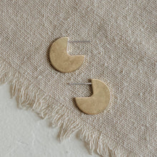 Load image into Gallery viewer, Pair of gold half-circle earrings on a textured beige fabric background
