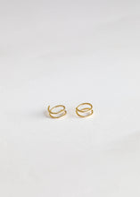 Load image into Gallery viewer, Pair of gold hoop earrings on a light gray background
