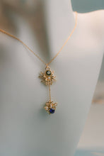 Load image into Gallery viewer, A gold chain necklace displayed on a white mannequin bust, featuring a dangling pendant with a gold spider-like motif and two small spider clusters, one with a dark green stone and the other with a deep blue stone.

