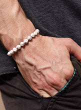 Load image into Gallery viewer, Close-up of an elderly hand wearing a white beaded bracelet on a dark background
