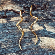 Load image into Gallery viewer, Gold snake-shaped earrings on a textured wooden surface
