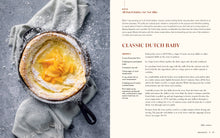 Load image into Gallery viewer, Dutch baby pancake with peaches on a skillet next to a recipe on a gray background
