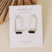 Load image into Gallery viewer, Gold and black onyx earrings on Jaxkelly branded card with dried leaves in the background
