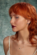 Load image into Gallery viewer, Woman with red hair wearing a necklace against a textured green background
