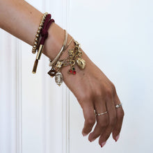 Load image into Gallery viewer, Hand wearing multiple bracelets with charms on a light background
