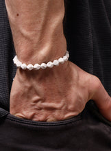 Load image into Gallery viewer, Close-up of a wrist wearing a white beaded bracelet against a black background
