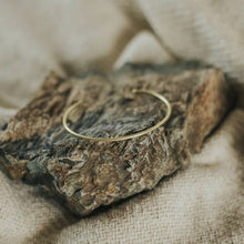 Load image into Gallery viewer, Gold bracelet on a textured stone surface with a neutral background

