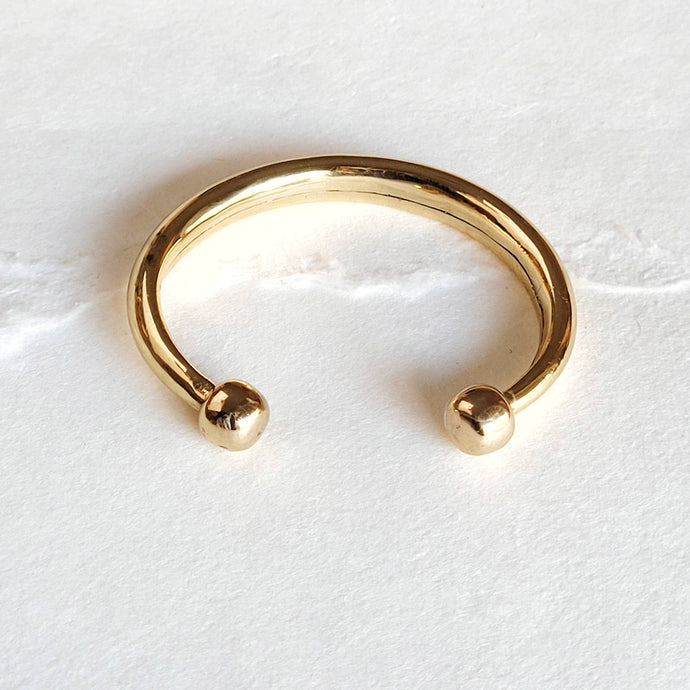 Gold brass cuff bracelet on a white marble surface