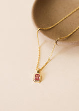 Load image into Gallery viewer, Gold necklace with a pink gemstone pendant on a beige background
