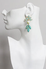 Load image into Gallery viewer, Pair of earrings with light blue floral tops and green leaves on a white bust
