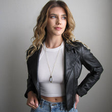 Load image into Gallery viewer, Woman wearing a black leather jacket over a white top and blue jeans against a plain background

