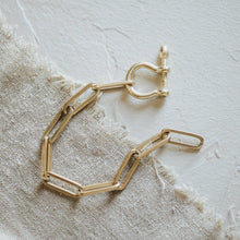 Load image into Gallery viewer, Gold bracelet on a textured beige fabric background
