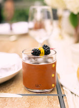 Load image into Gallery viewer, Glass wrapped in brown leather with blackberries on a table setting
