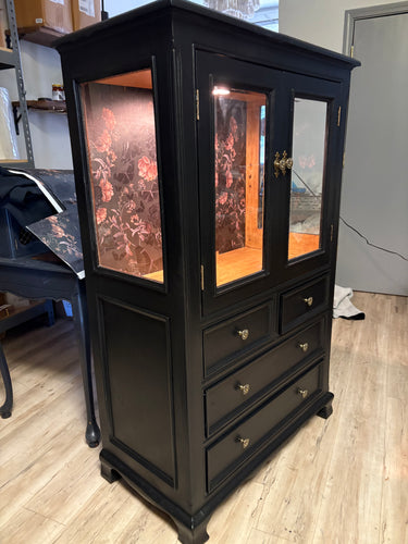 Black wooden cabinet with glass panels on a wooden floor