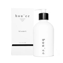 Load image into Gallery viewer, A bottle of Riddle Boujee Body Oil with a pump dispenser, next to its packaging box. The bottle and box are white with black text, and the product is named 'boujee' with a subtitle 'kismet'.
