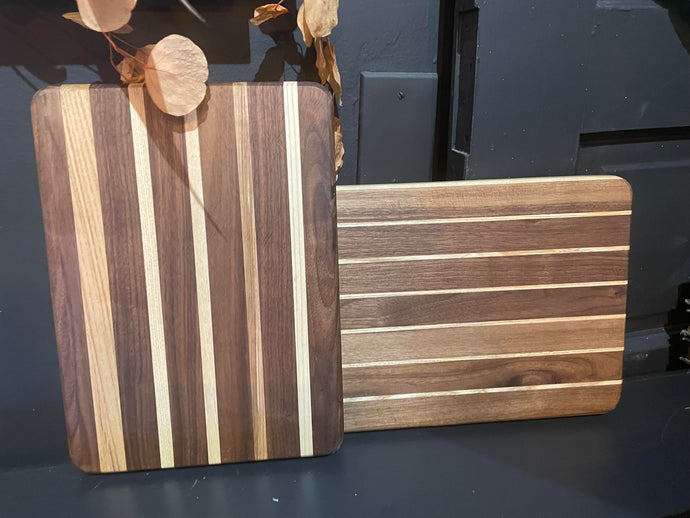 Two wooden cutting boards with striped pattern on a dark surface