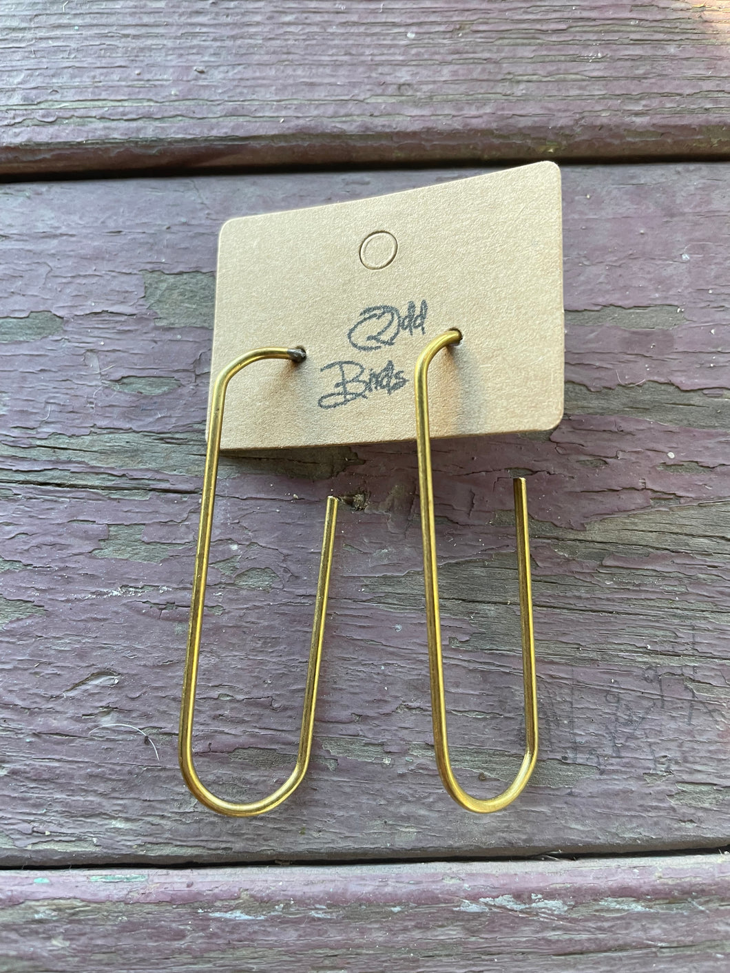 Solid smooth raw brass elongated hoop earrings on a 2 Odd Bird display card.