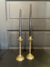 Load image into Gallery viewer, Two tall candlesticks with brass bases and black candles on a dark surface.

