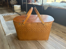 Load image into Gallery viewer, Wicker picnic basket with wooden handles on a wooden floor.
