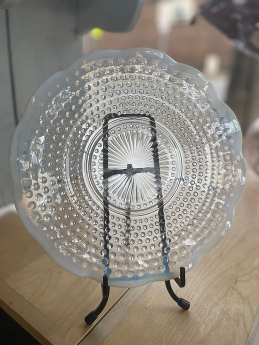 Decorative glass plate with a textured design on a stand