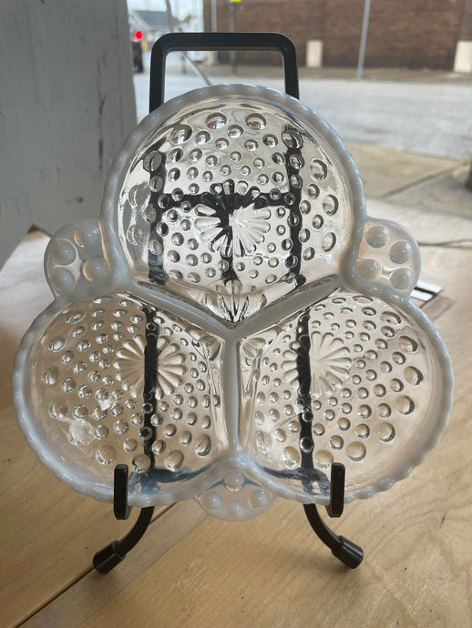 Clear glass hobnail divided dish  with white embossed patterns on a plain background