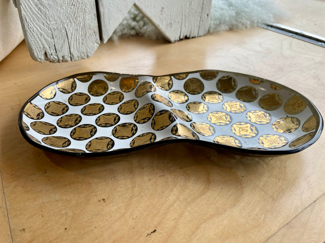 Divided glass dish with gold and black medallion motif on a wooden surface