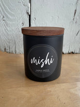 Load image into Gallery viewer, Black candle jar with wooden lid on a wooden surface, featuring the brand 'mishi'.
