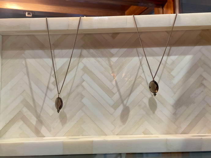 Two necklaces on a marble surface with a chevron pattern
