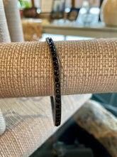 Load image into Gallery viewer, Black crystal bracelet on a textured surface with a blurred indoor background
