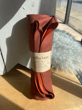 Load image into Gallery viewer, Brown fabric roll with a label on a wooden surface

