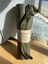Load image into Gallery viewer, Rolled-up green scarf with a label on a wooden surface
