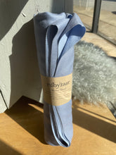 Load image into Gallery viewer, Light blue scarf with a label on a wooden surface
