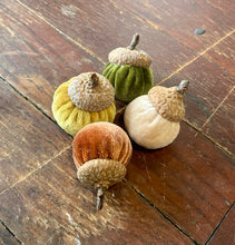 Load image into Gallery viewer, Four velvet acorn decorations in yellow, green, peach, and cream, arranged on a rustic dark wood plank surface.
