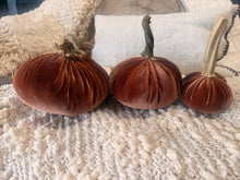 Load image into Gallery viewer, Three velvet decorative pumpkins in shades of rust, terracotta, and dark brown, styled on a chunky knit cream blanket with neutral pillows in the background.
