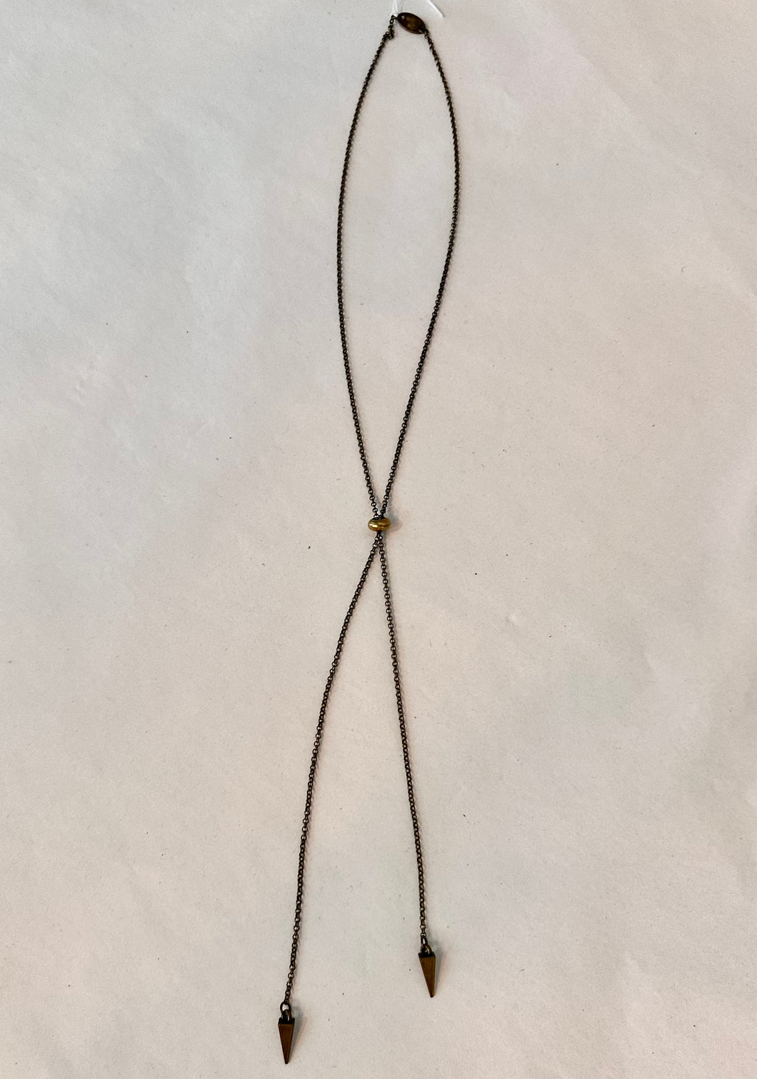 Necklace with arrow-shaped ends on a light beige background